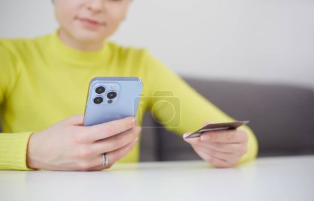 Foto de Mujer joven que paga en línea con una tarjeta de crédito y un teléfono inteligente. Persona femenina irreconocible haciendo una compra en la aplicación móvil - Imagen libre de derechos