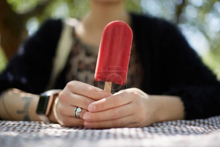 Foto de Chica joven sosteniendo un postre de helado natural en las manos. Mujer sostiene un helado de arándano orgánico en palo - Imagen libre de derechos
