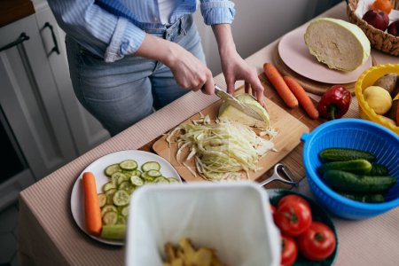 Photo for The cook preparing vegetables and recycling organic leftovers in a compost bin. Responsible female person leading a healthy and sustainable lifestyle - Royalty Free Image