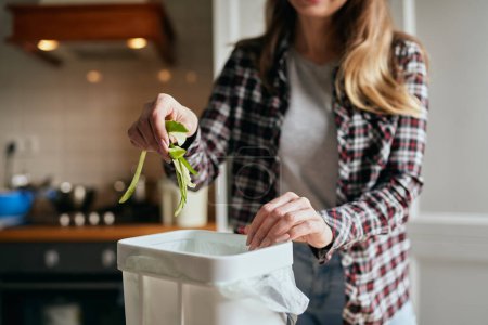 Photo for Female person throwing organic food waste in a compost bin. Responsible woman recycling cucumber peels in a bokashi container at home. Sustainability concept - Royalty Free Image