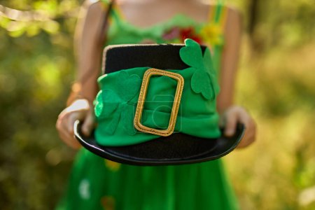 Photo for Little girl holding a leprechaun hat with green ribbon and clover symbol - Royalty Free Image