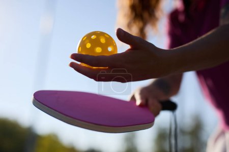 Pickle ball player serving a ball with a paddle racquet