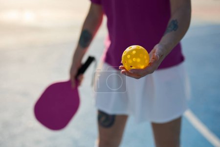 Pickler athlete practicing to serve a plastic ball with a paddle racket
