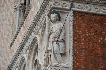 Photo for Statue of archangel Raphael wit a spear on the exterior of the Doge's Palace (Italian: Palazzo Ducale), one of the main Venetian landmarks. Venice - 5 May, 2019 - Royalty Free Image
