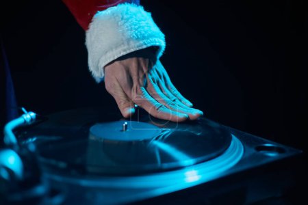 Photo for Hip hop DJ in red Santa costume scratching a vinyl record on turntable deck - Royalty Free Image