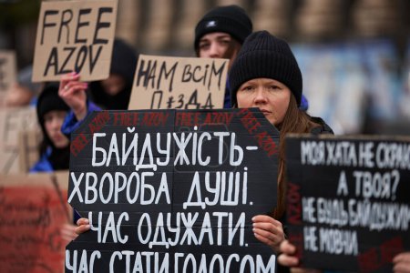 Foto de Mujer ucraniana posando con una pancarta "La indiferencia es la enfermedad de un alma. Time To Heal "en una manifestación dedicada a los defensores capturados de Ucrania. Kiev - 18 de febrero de 2024 - Imagen libre de derechos