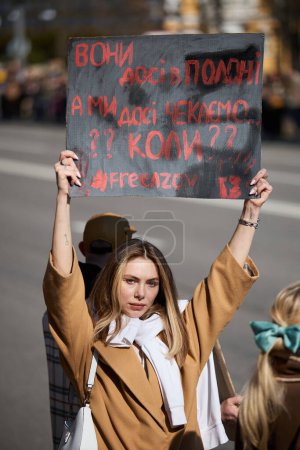 Photo for Young Ukrainian woman posing with a banner "They Are Still Captured. We Are Still Waiting. Free Azov" on a demonstration dedicated to captured defenders of Azovstal and Mariupol. Kyiv - 10 March,2024 - Royalty Free Image