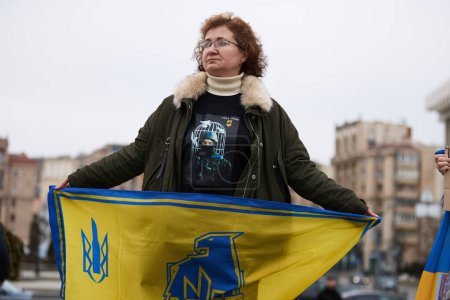 Foto de Mujer ucraniana sostiene una bandera de la brigada Azov en una manifestación pública. Kiev - 16 de marzo de 2024 - Imagen libre de derechos