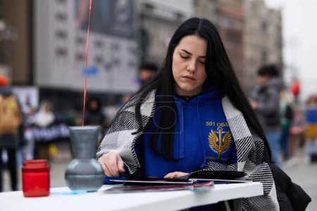 Photo for Wife of missing Ukrainian soldier browsing their photos on a public performance "Two Captured Hearts" at the Maidan square. Kyiv - 16 March,2024 - Royalty Free Image