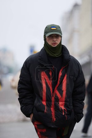 Foto de Activista camina en un abrigo con el logotipo de la brigada nacionalista ucraniana Azov en una manifestación pacífica. Kiev - 17 de marzo de 2024 - Imagen libre de derechos
