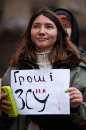 Photo for Cheerful Ukrainian female holds a banner "Money On Army" at a public gathering in support of Armed Forces. Kyiv - 23 March,2024 - Royalty Free Image