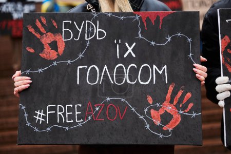 Foto de La persona sostiene una pancarta "Sé su voz. Free Azov "en una manifestación. Kiev - 24 de marzo de 2024 - Imagen libre de derechos