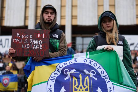 Foto de Activistas posando con una bandera de la Guardia Costera Ucraniana y una pancarta "Fui capturado, sé lo que es un infierno" en una protesta pública. Kiev - 24 de marzo de 2024 - Imagen libre de derechos
