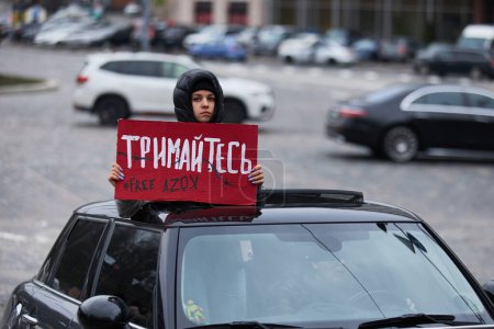 Foto de Activista mostrando una pancarta "¡Aguanta! Azov libre "de un coche en movimiento en una manifestación pública en Kiev - 24 de marzo de 2024 - Imagen libre de derechos