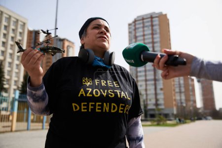 Photo for Ukrainian activist Hanna Kurtsanovska talks on camera with a helicopter in hand as a symbol of defenders of Mariupol and Azovstal. Kyiv - 31 March,2024 - Royalty Free Image