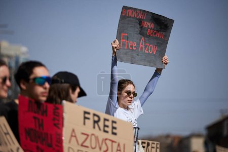 Photo for Young Ukrainian woman protesting against russian captivity with a banner "There Are No Spring In Prison. Free Azov" on a public demonstration. Kyiv - 31 March,2024 - Royalty Free Image