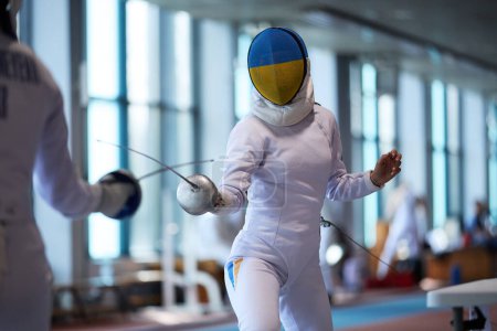 Photo for National Fencing Team Member in a protective mask painted in colors of Ukrainian flag, fighting with the epee blade at the Championship of Ukraine. Kyiv - 30 March,2024 - Royalty Free Image