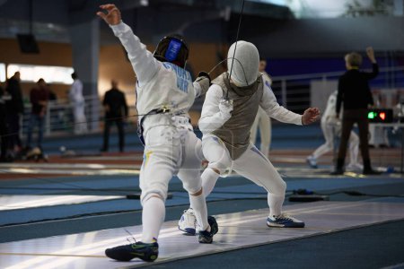 Photo for Fencers wearing protective lame jackets and masks fight during the National Fencing Championship of Ukraine. Kyiv - 30 March,2024 - Royalty Free Image