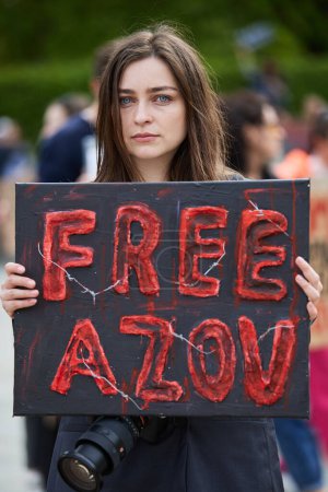 Photo for Cute Ukrainian girl posing with a banner "Free Azov" on a public demonstration. Kyiv - 14 April,2024 - Royalty Free Image