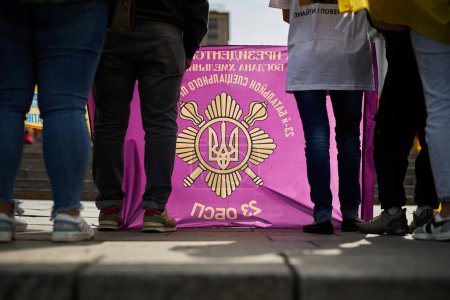Photo for Ukrainians hold the coat of arms with traditional golden trident symbol on a demonstration. Kyiv - 13 April,2024 - Royalty Free Image
