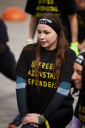 Young Ukrainian female warming up and stretching before a marathon distance run at the Spartan Race competition in Kyiv - 20 April,2024