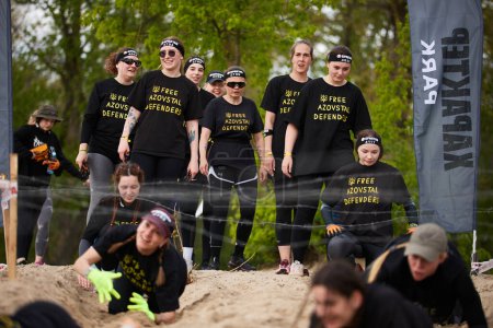 Photo for Group of Ukrainian women take part in the barbed wire crawl discipline at the Spartan Race competition in Kyiv - 20 April,2024 - Royalty Free Image