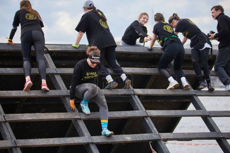 Foto de Grupo de mujeres escalando el obstáculo del muro de deslizamiento en la competición Spartan Race en Kiev - 20 de abril de 2024 - Imagen libre de derechos
