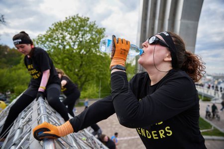 Photo for Woman drinks water on top of a "A-Frame" pyramid at the Spartan Race competition in Kyiv - 20 April,2024 - Royalty Free Image