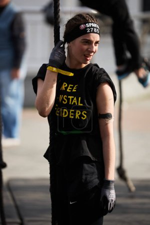 Foto de Retrato de una joven alegre participando en una disciplina de escalada de cuerdas en la competición Spartan Race en Kiev - 20 de abril de 2024 - Imagen libre de derechos