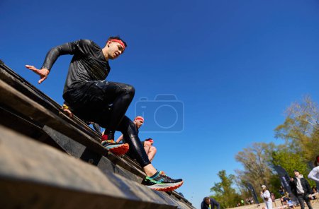Foto de Atletas ucranianos subiendo por encima del obstáculo del muro de deslizamiento en la competición de Spartan Race en Kiev - 20 de abril de 2024 - Imagen libre de derechos