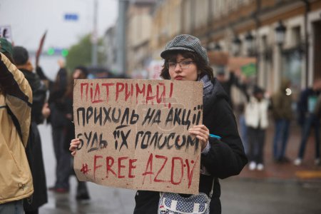 Foto de Joven mujer ucraniana posando con una pancarta "Visita las manifestaciones. Apoyo. Free Azov "en una manifestación en Kiev - 21 de abril de 2024 - Imagen libre de derechos