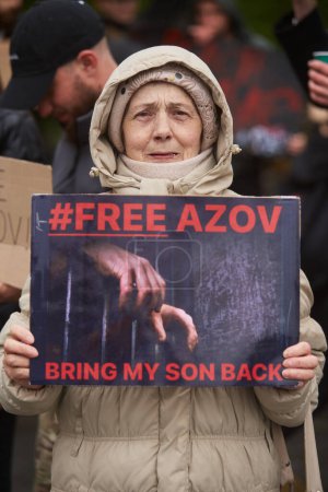 Photo for Senior Ukrainian woman with tears in her eyes posing with a banner "Bring My Son Back. Free Azov" on a public demonstration in Ukraine. Kyiv - 21 April,2024 - Royalty Free Image
