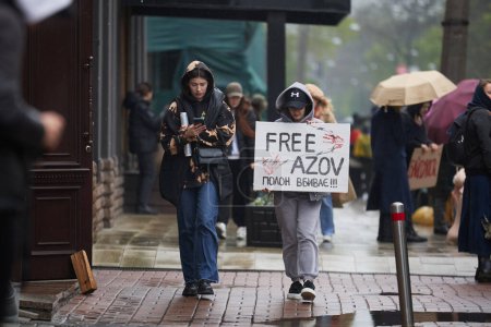 Téléchargez les photos : Les jeunes filles ukrainiennes marchant avec une bannière "Azov libre" sur une manifestation publique dans la pluie Kiev - 21 avril, 2024 - en image libre de droit