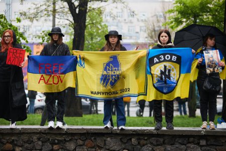 Téléchargez les photos : Jeunes filles ukrainiennes posant avec des drapeaux nationaux et symbole o Brigade Azov lors d'une manifestation publique dédiée aux défenseurs capturés de la ville de Marioupol et Azovstal. Kiev - 21 Avril, 2024 - en image libre de droit