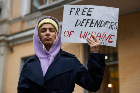 Foto de Joven ucraniana posando con una pancarta "Defensores Libres de Ucrania" en una manifestación pública en Kiev - 21 de abril de 2024 - Imagen libre de derechos