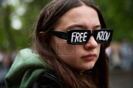 Foto de Chica joven con gafas de sol con una escritura "Free Azov" en un evento público en Kiev - 21 de abril de 2024 - Imagen libre de derechos
