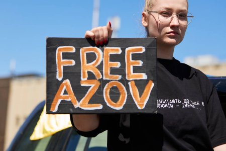 Photo for Young Ukrainian woman rides in a car with a sign Free Azov in hands. Kyiv - 28 April,2024 - Royalty Free Image