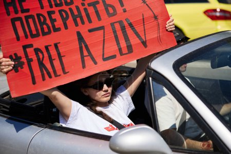 Photo for Young Ukrainian woman riding in a cabrio with a large banner "Free Azov" on a public demonstration. Kyiv - 28 April,2024 - Royalty Free Image