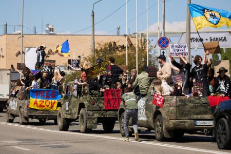 Foto de Camiones militares ucranianos con un grupo de activistas montados con pancartas y banderas en una manifestación pública por la liberación de la brigada Azov de las prisiones rusas. Kiev - 28 de abril de 2024 - Imagen libre de derechos