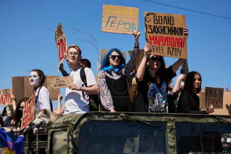 Foto de Grupo de diversos jóvenes ucranianos montados en un camión militar con letreros "Free Azov" en una manifestación pública. Kiev - 28 de abril de 2024 - Imagen libre de derechos