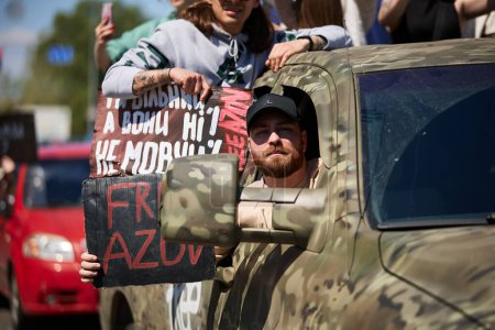 Foto de La cantante ucraniana Gera Gerc monta en un camión camuflado con un letrero "Free Azov". Kiev - 28 de abril de 2024 - Imagen libre de derechos