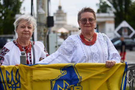 Photo for Senior Ukrainian ladies wearing traditional vyshyvanka shirts demonstrating with flag of Azov brigade in Kyiv - 5 May,2024 - Royalty Free Image