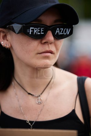 Photo for Ukrainian activist wearing sunglasses with a writing "Free Azov" and pacific sign on her neck at a peaceful demonstration in Kyiv - 5 May,2024 - Royalty Free Image