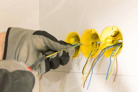Foto de Electrician hands mounting electric wall receptacle, fitting into place - Imagen libre de derechos