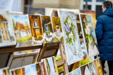 Téléchargez les photos : VILNIUS, LITHUANIA - MARCH 4, 2022: Painters sell their paintings on Kaziuko muge or Kaziukas, traditional Easter market, crafts fair held every March on Old Town streets. - en image libre de droit