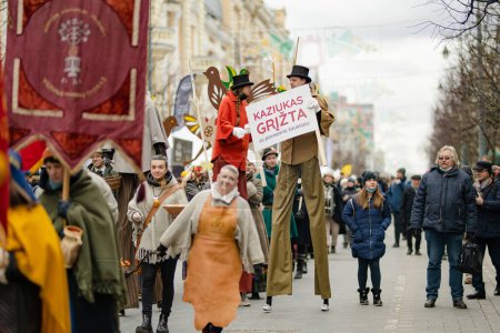 Foto de VILNIUS, LITHUANIA - MARCH 4, 2022: Cheerful people participating in humorous parade during Kaziuko muge or Kaziukas, traditional Easter market, crafts fair held every March on Old Town streets. - Imagen libre de derechos