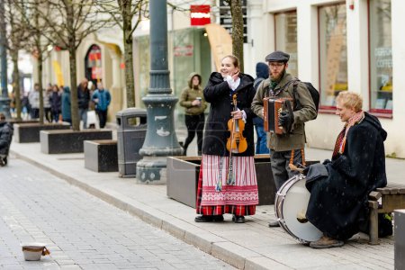 Téléchargez les photos : VILNIUS, LITHUANIA - MARCH 4, 2022: Folk singers and musicians playing music during Kaziuko muge or Kaziukas, traditional Easter market, crafts fair held every March on Old Town streets. - en image libre de droit