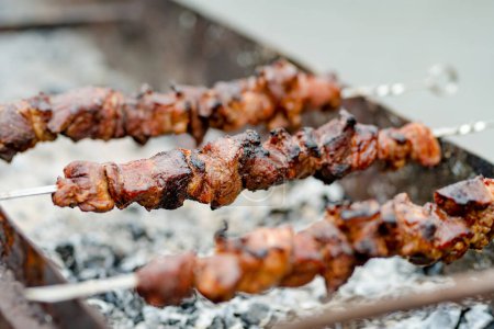 Foto de Chicken kabobs grilled on metal skewers outdoors. Eating outdoors in summer. - Imagen libre de derechos