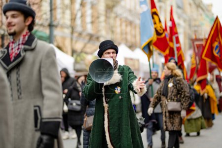 Foto de VILNIUS, LITHUANIA - MARCH 4, 2022: Cheerful people participating in humorous parade during Kaziuko muge or Kaziukas, traditional Easter market, crafts fair held every March on Old Town streets. - Imagen libre de derechos