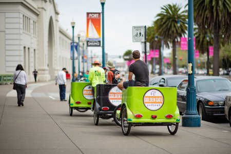 Photo for SAN FRANCISCO, USA - APRIL 2016: Young pedicab drivers wait for clients on downtown street in San Francisco, USA. - Royalty Free Image